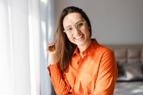 istock Smiling woman in eyeglasses looking at camera while posing at home 2155681616
