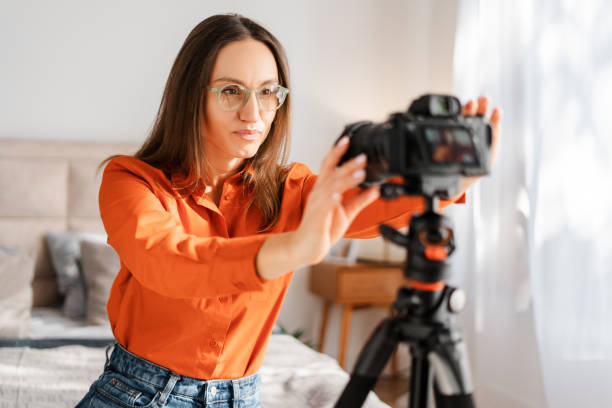 istock Positive happy woman adjusting camera on tripod, smiling, preparing for online conference 2155681629
