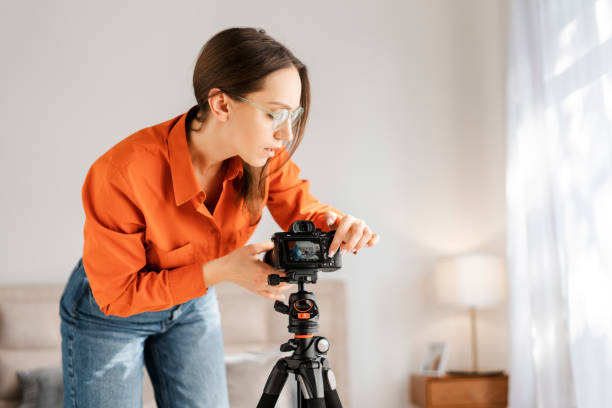 istock Positive happy woman adjusting camera on tripod, smiling, preparing for online conference 2155681633