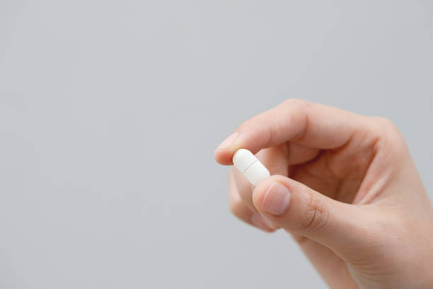 istock close up hand man taking multiple pills take a medicine in hand holding a cup glass of drinking water on wooden table. Stop drug use Taking Medication health care medical concept. 2155681966
