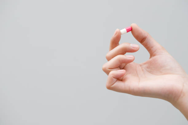 istock close up hand man taking multiple pills take a medicine in hand holding a cup glass of drinking water on wooden table. Stop drug use Taking Medication health care medical concept. 2155682001