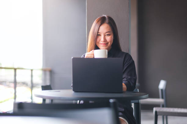 istock Portrait image of a young woman drinking coffee while working on laptop computer in cafe 2155683110