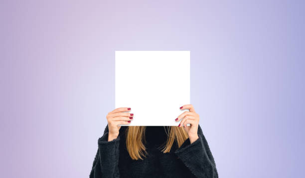 istock Young woman hiding face with blank mock up banner, colored background 2155685284