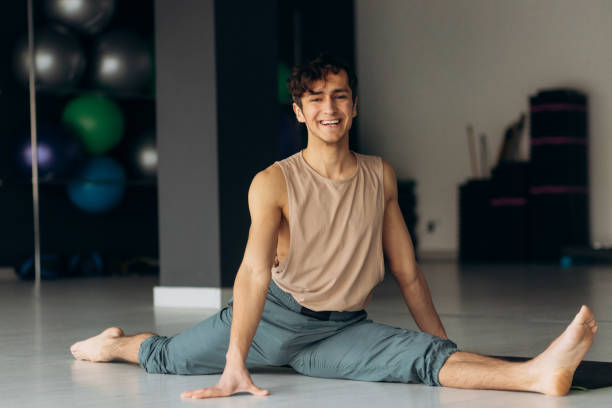 istock Fit guy does front leg split workout exercise in studio. Handsome man trains at home. Sports lifestyle 2155686603