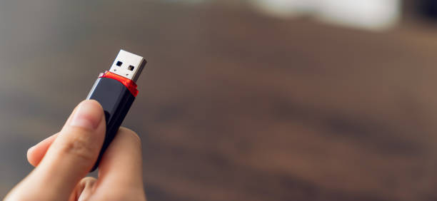 istock Hand holding usb flash drive with connecting to laptop at wooden table 2155688559