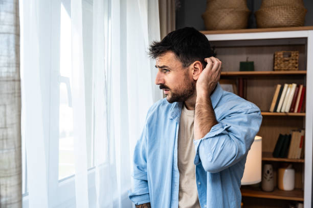 istock Young sad and depressed man feeling regret and anxiety, standing near window looking through. Mental burnout after hard work and hours of insomnia. Relationship difficulties desperation and depression 2155691988