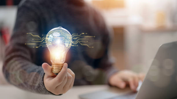 istock A person is holding a light bulb in their hand, with a laptop in front of them 2155694780