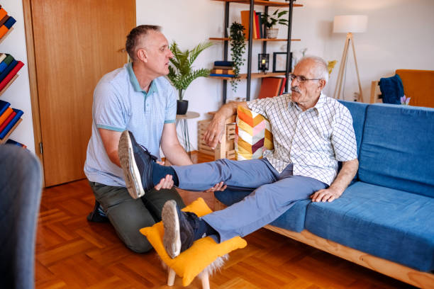 istock Man taking care of old people at home supporting with stretching exercise 2155695675