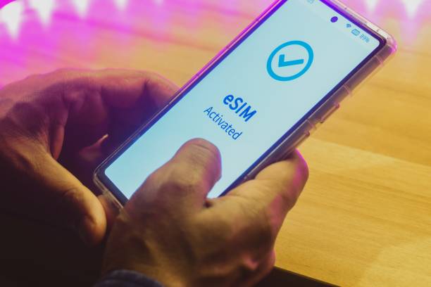 Mobile phone displaying the message eSIM activated. Digital SIM or embedded SIM to allow cellular connection, night time, close up image.