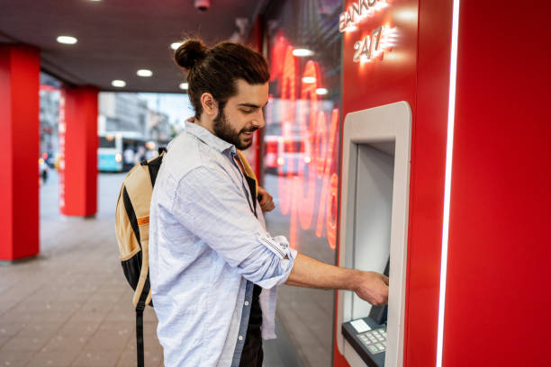 istock Young man withdrawing money from a cash machine 2155702646