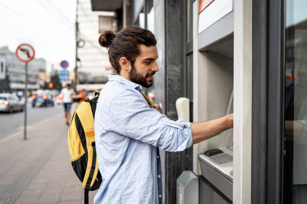 istock Young man withdrawing money from a cash machine 2155702784