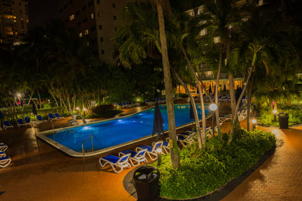 Miami Beach. USA. 06.02.2024 Serene night atmosphere envelops the Radisson hotel, accompanied by swaying palm trees beside a shimmering outdoor pool.