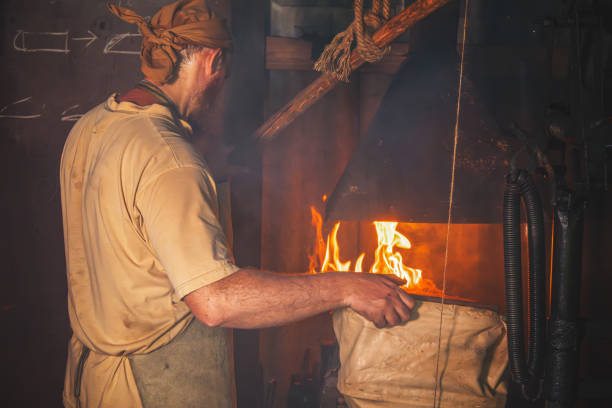 istock Blacksmith in an authentic forge fans the fire with hand-held bellows. Traditional crafts 2155704853