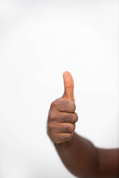 black Hand making thumbs up sign gesture over white background, frontal view, foreshortening