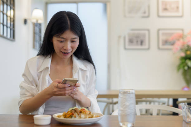 istock A young woman using a smartphone while dining at a modern and relaxed restaurant 2155709770