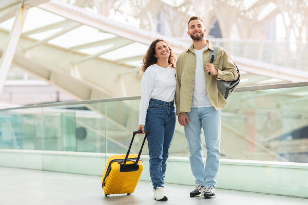 istock Couple with luggage smiling at terminal 2155714322