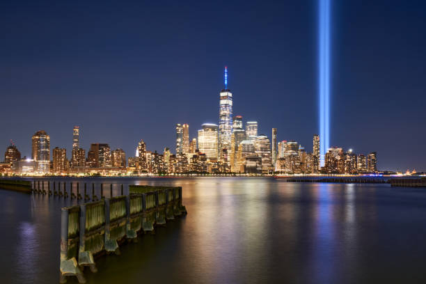istock Lower Manhattan skyscrapers and September 11 Tribute in Light reflecting in Hudson River. Two vertical beams of light rise near World Trade Center in New York City 2155716128