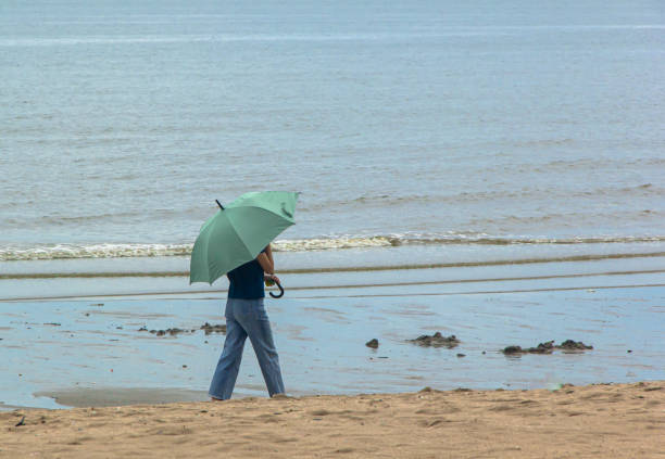 young girl walking with umbrella on the beach