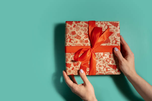 istock Wrapping up the season, hand presenting a Christmas present on green background 2155725045