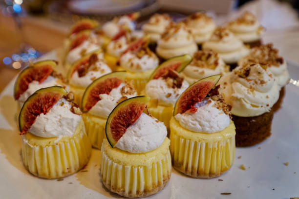 A plate full of small cupcakes with cream and fig pieces toppings.