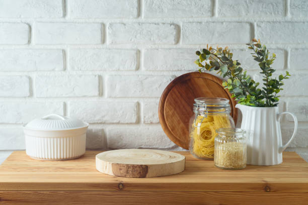 istock Empty wooden log  on kitchen table with food jars and plants over white brick wall  background.  Kitchen mock up for design and product display. 2155742087