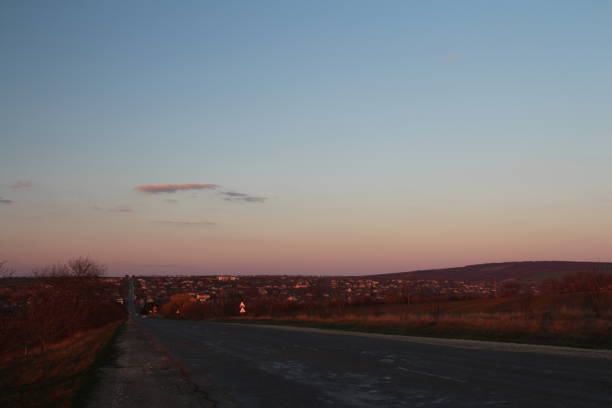 A large airplane flying over a city. Sky. Outdoor. Sunset. Distance. Day