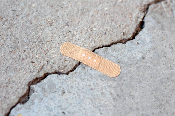 Broken asphalt roads, caused by earthquake. A large crack in concrete. Cracked concrete fixing with a medical plaster