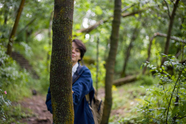 Short-haired young lady spending time among the trees in the park, resting, strolling, drinking tea