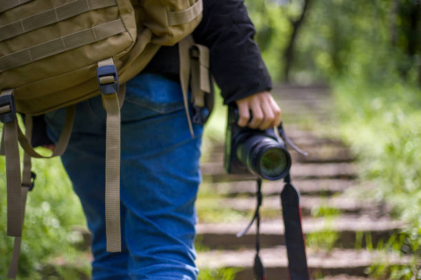 Young woman nature photographer is shooting with a camera in the wooded area