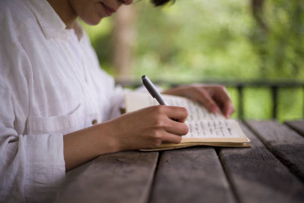 istock young woman reading a book and writing in a camellia 2155757819