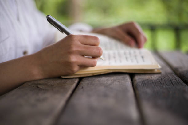 istock young woman reading a book and writing in a camellia 2155757897