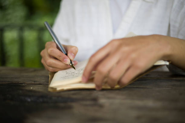 istock young woman reading a book and writing in a camellia 2155757899