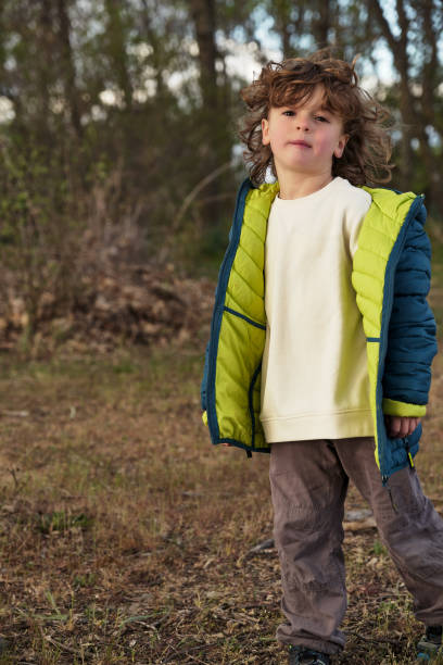 istock Cute boy in warm jacket standing in daylight 2155758689
