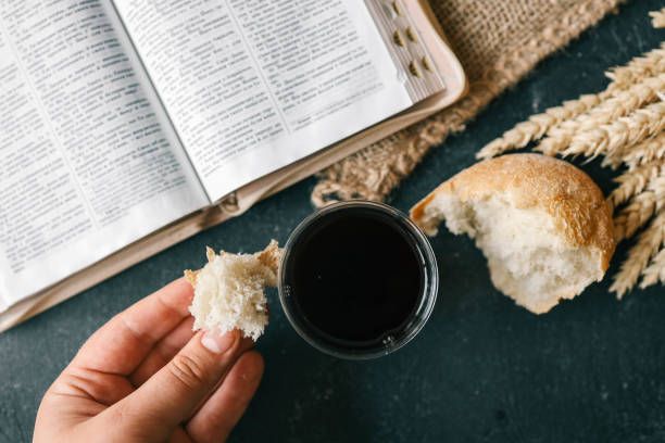istock Cup with wine, bread and open Bible, Christian communion 2155760355
