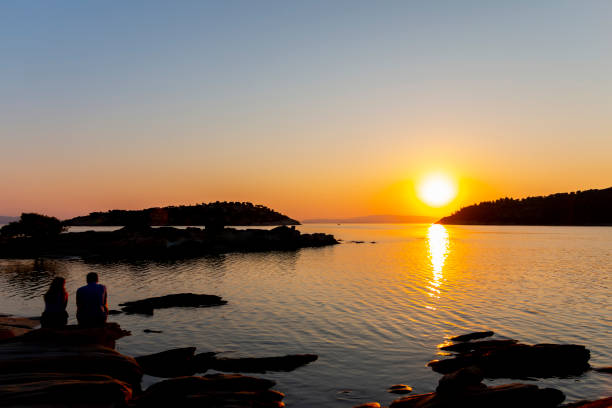 istock As the sun dips below the horizon, casting a warm orange glow across the sky, a striking silhouette emerges on the beach. The serene scene captures the tranquil beauty of nature and the intimacy of the moment that the couple shares. 2155772111