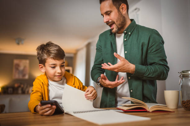 istock Father with book help son who copy notes from mobile phone at home 2155772245