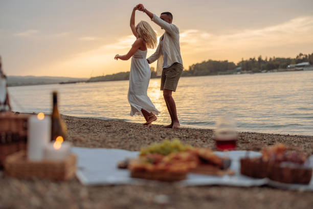 Interracial couple swirling in dance by the river Interracial couple in love is by the river side, happily dancing the evening away at sunset after enjoying a delightful picnic. black couple sunset stock pictures, royalty-free photos & images