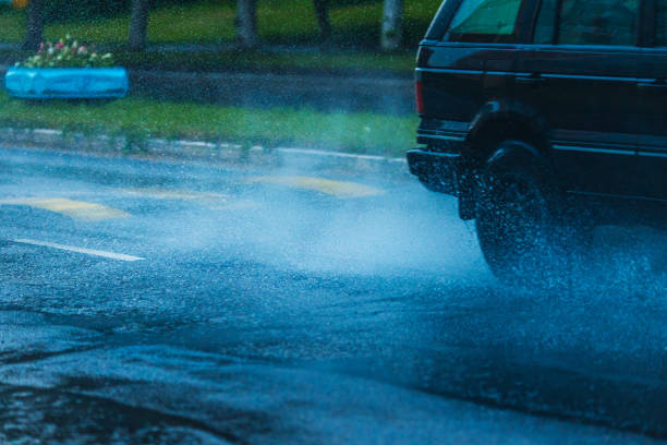 Raindrops on the windshield on a rainy day; blurred car stopped at a traffic light in the background; California