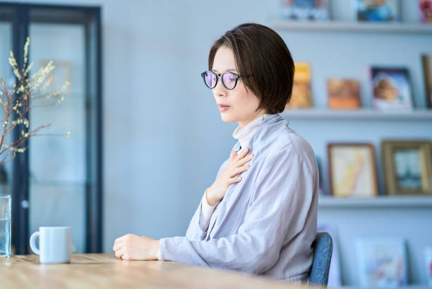 a woman who seems to feel discomfort in her throat - ストレス ストックフォトと画像