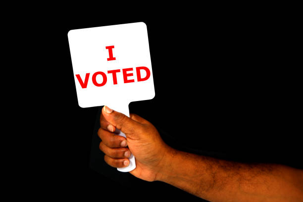 I VOTED hand holding sign board with black background close-up view copy space