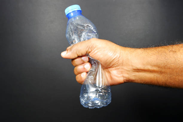 Crushing a plastic bottle by hand on black background, Ban plastic concepts