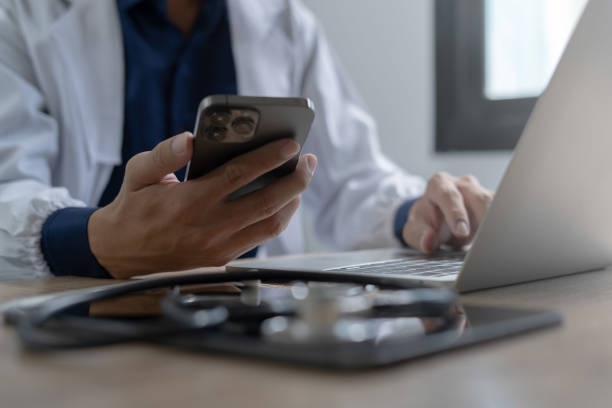 istock Doctor using mobile smartphone working on laptop computer in medical office Close the teleconference telemedicine 2155793304