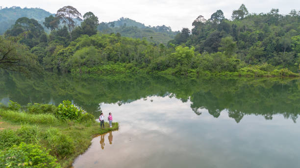 Two Asian female mountain hiking relax near lakeshore.
