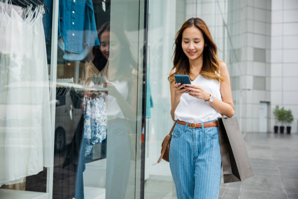 istock person looking at her phone while standing against a city wall 2155795536