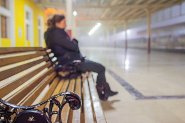 Lonely woman waiting for the delayed train sits on the bench at the train station at night . Sivas , Türkiye