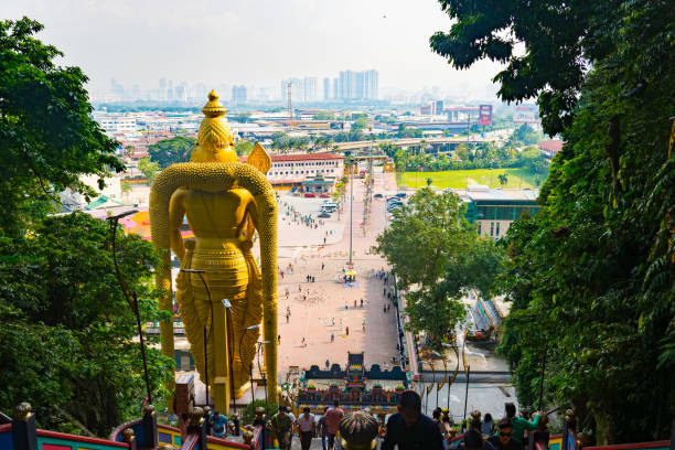 Kuala Lumpur, Malaysia - May 15, 2024 : Arulmigu Murugan Statue in Batu Caves with Kuala Lumpur in Background