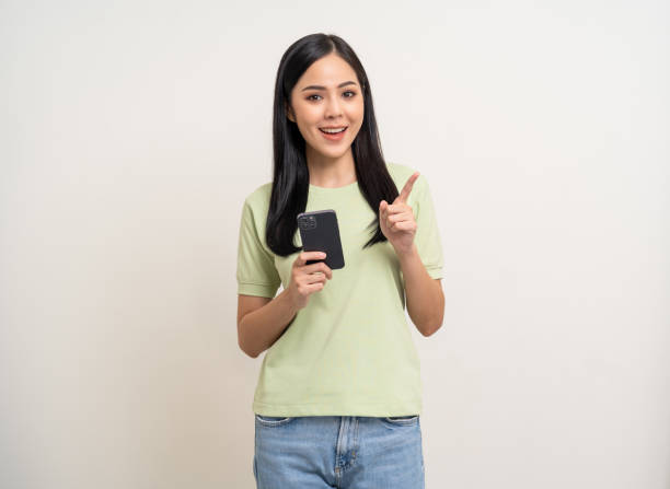 istock Pretty young asian woman using cellphone standing on isolated white background. Happy Excited Beautiful young asian shopping online payment with mobile phone. Playing game on smartphone 2155802126