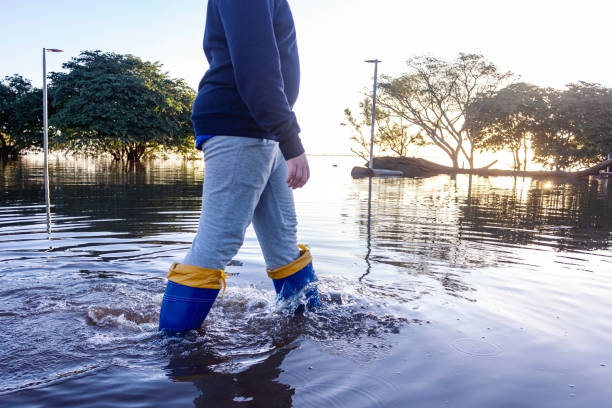 istock Child protected with galoshes walking in flooded area 2155803002