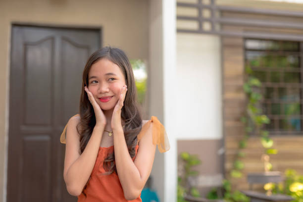 istock A young lady puts both of her hands on her cheeks as she acts cute for the camera. 2155803312