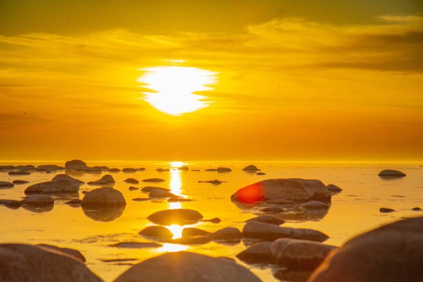 Sun is setting over the rocky pier to calm sea. Romantic view to stones in sea during sunset